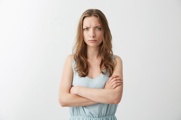 Offended displeased young girl frowning with crossed arms .