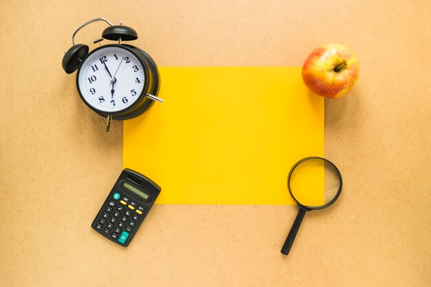 Office accessories and apple laid on piece of paper