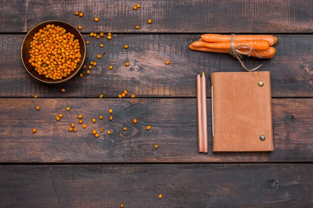 Office desk table with notebooks, fresh buckthorn berries on wooden table