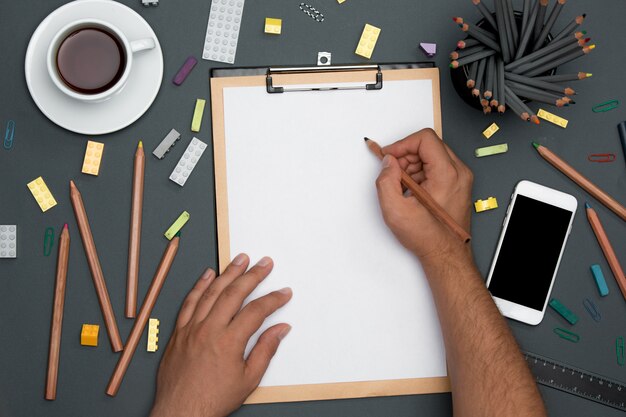 Office desk table with pencils, supplies, phone and male hands