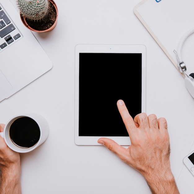 Office desk with finger pointing at tablet