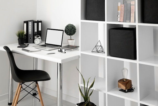 Free photo office desk with laptop and chair next to shelf