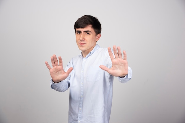 office employee in formal wear showing stop gesture on gray wall.