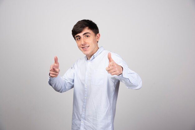 office employee in formal wear showing thumbs up on gray wall.