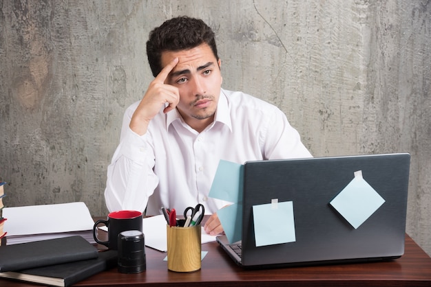 Office employee looking at laptop at the office desk.