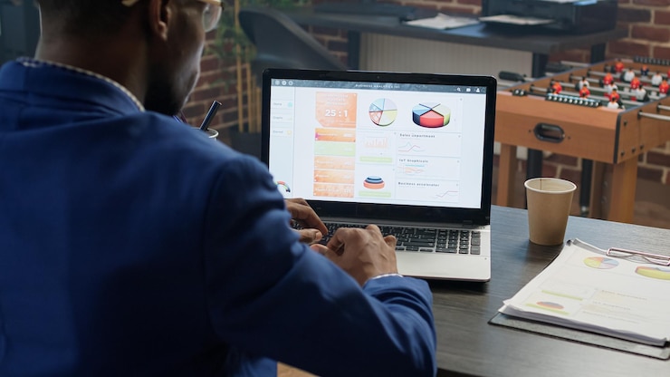 Free Photo office employee working with data statistics at desk, using laptop to plan business charts and browsing internet. project manager analyzing diagrams and paperwork on online network.