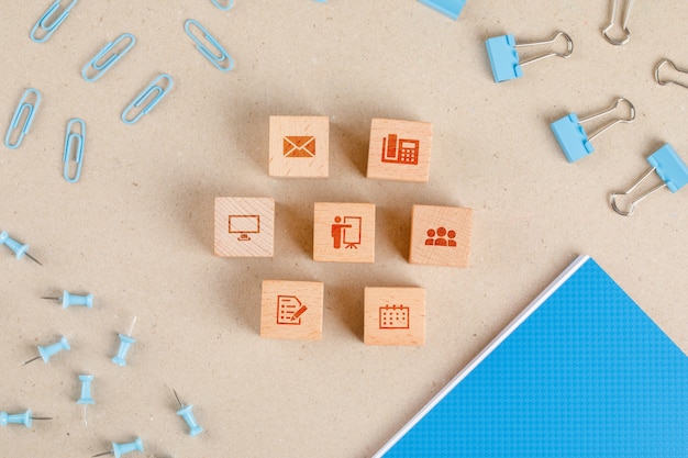 Free photo office supplies concept with icons on wooden cubes, stationery set flat lay.