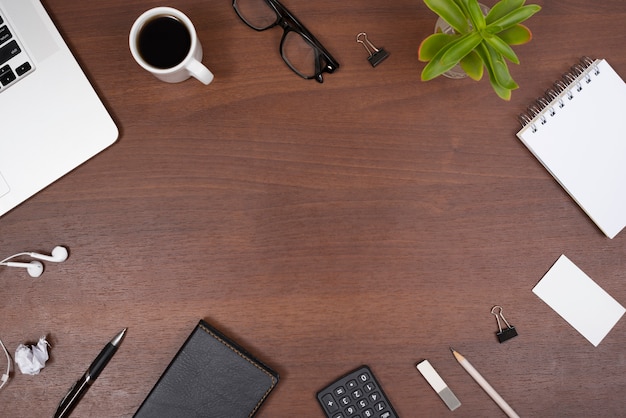 Office supplies; gadgets; cup of tea and plant with earphones on a wooden table