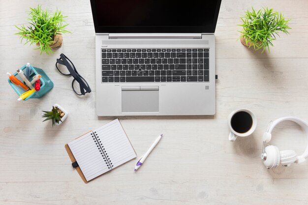 Office supplies with laptop; headphone and coffee cup on wooden desk