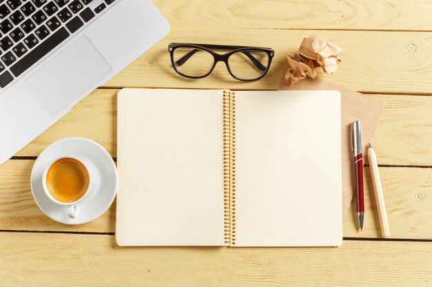 コーヒーカップ、鉛筆、コンピューターのキーボードとオフィステーブルの背景。ビジネスワークプレイスまたはワークスペースの概念。