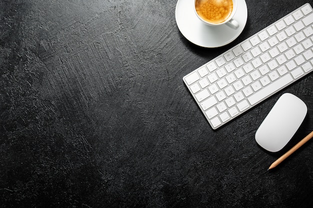 Office table with cup of coffee, keyboard and notepad