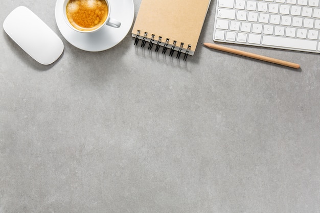 Office table with cup of coffee, keyboard and notepad