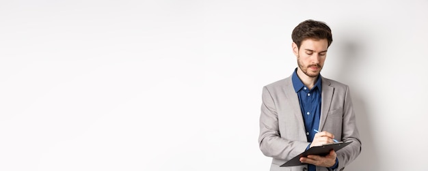 Free photo office worker in suit writing on clipboard taking notes on meeting standing on white background