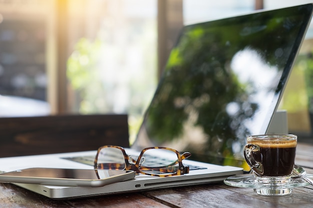 Office workplace with laptop and glasses on wood table