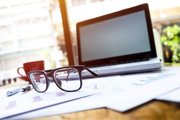 Office workplace with laptop and glasses on wood table