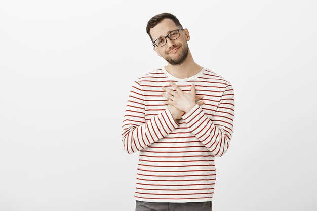 Oh it is so sweet. Portrait of cute pleased man in glasses, standing touched