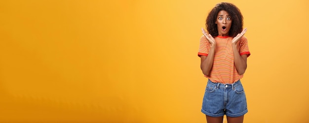 Free photo oh no what happened worried african american sister with curly hair in trendy striped tshirt and den