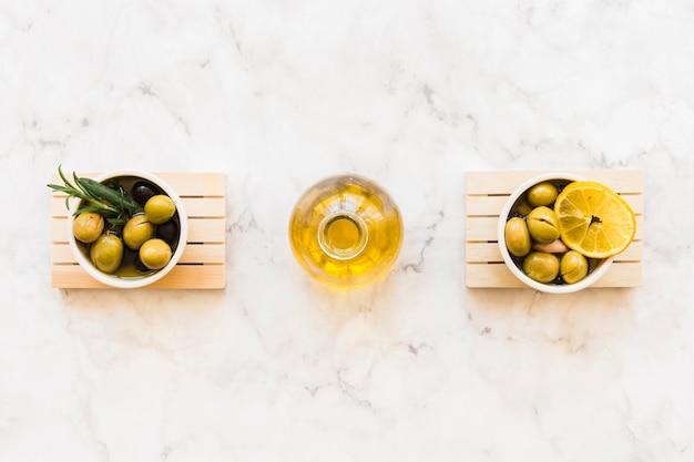 オリーブの2つのボールの間にあるオイルボトル、ローズマリーとレモンスライス