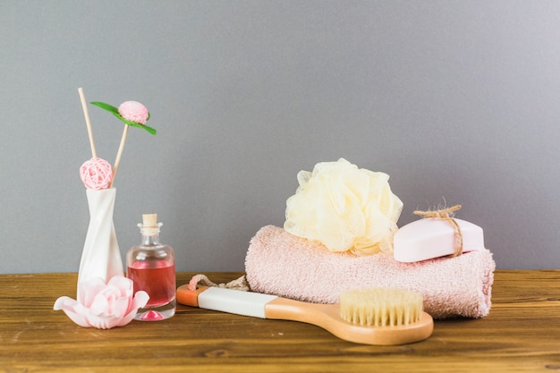 Oil; brush; towel; loofah and soap on wooden tabletop