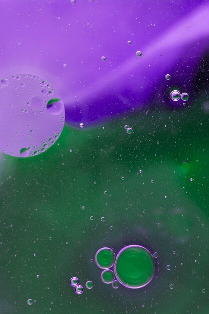 Oil bubbles floating on green and purple watercolor background