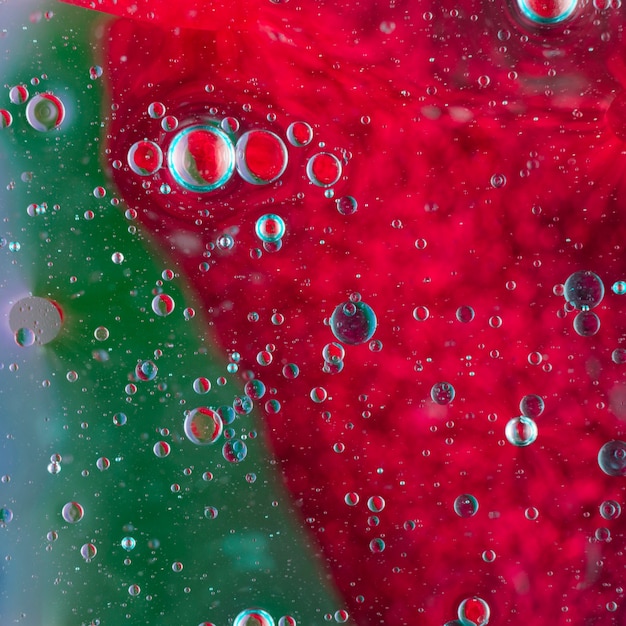 Oil bubbles floating on green and red water surface