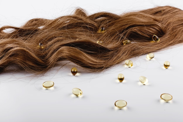 Бесплатное фото Масляные капсулы с витамином е лежат на коричневых волосах