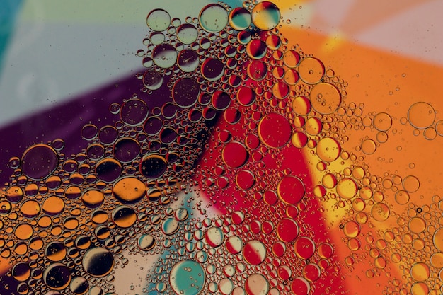 Oil drops in water on a coloured background