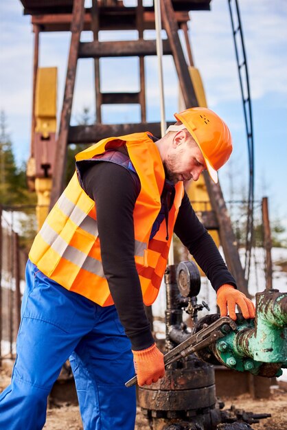 Oil man tightening lug nuts with industrial wrench in oil field