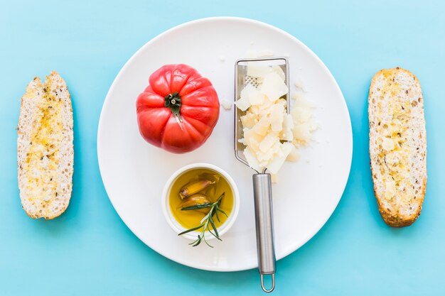 Oil with tomato and grated cheese on plate with two slice of bread over the blue background