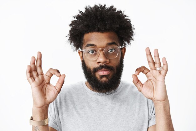 Ok count it done Portrait of goodlooking assured and assertive african american male coworker in glasses with pierced nose beard and afro hairstyle showing okay gesture liking and accepting plan