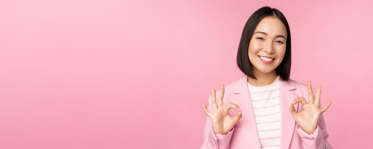 무료 Photo ok 승인 제스처를 보여주는 기업 정장을 입은 훌륭한 사업가가 긍정적인 피드백을 주고 분홍색 배경 위에 포즈를 취한 것을 기쁘게 생각합니다.