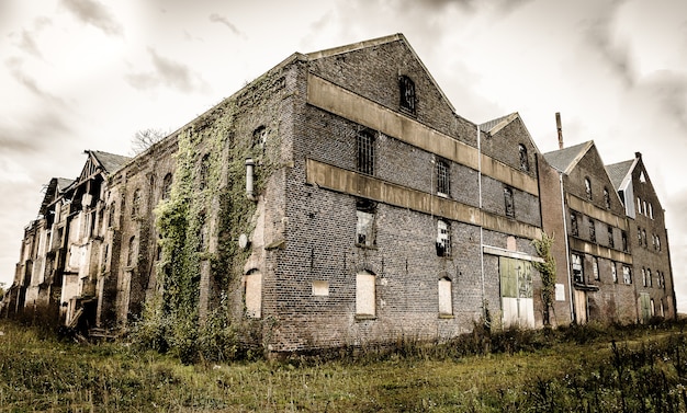 Old abandoned stone building with broken windows under the dark cloudy sky