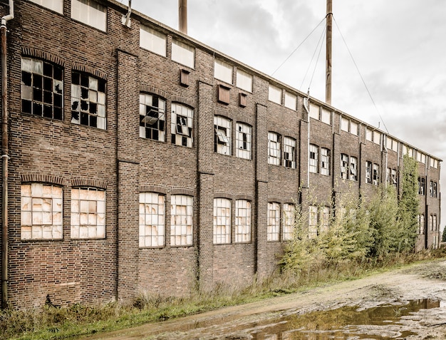 Old abandoned stone building with broken windows and a puddle outside