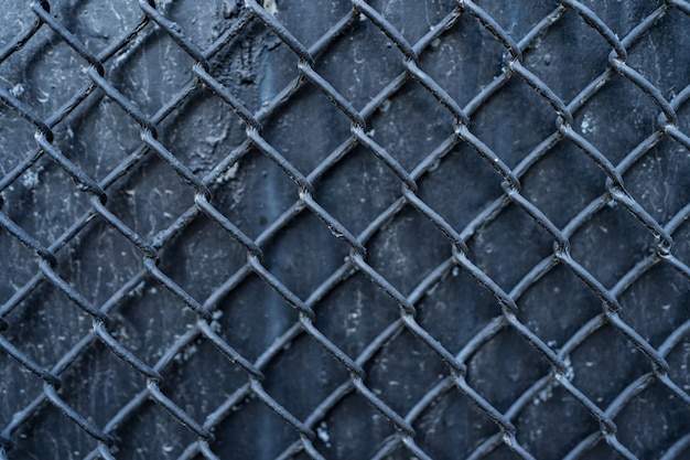 Old black metal background covered with wire mesh grille. Metal texture