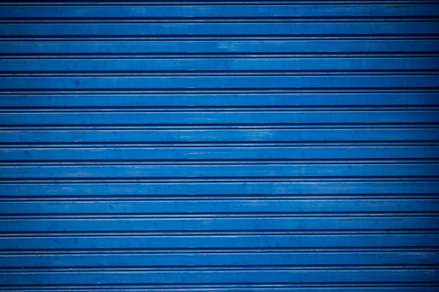 古い青いシャッターは金属製のドアをロールアップします。