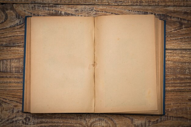 Old book open on a wooden table seen from above