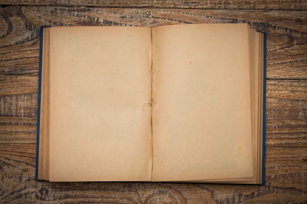 Old book open on a wooden table seen from above