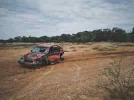 Free photo old broken up car in a dry grass field with trees