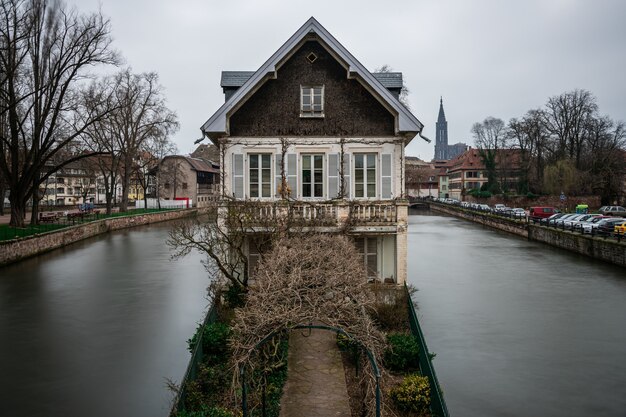 Old building surrounded by water and greenery under a cloudy sky in Strasbourg in France