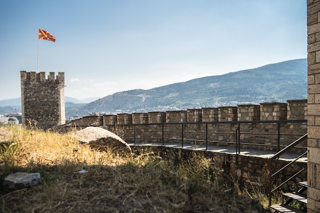 緑に覆われた丘に囲まれたマケドニアの旗のある古城
