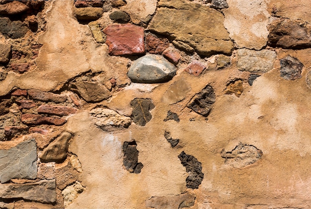 Old cement wall with stones in it
