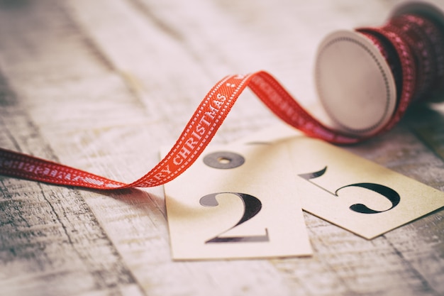 Free photo old christmas concept - red ribbon with letters merry christmas on an old wooden background, closeup