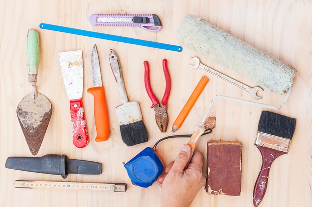 Old construction hand tool set with worker hand over white wooden background