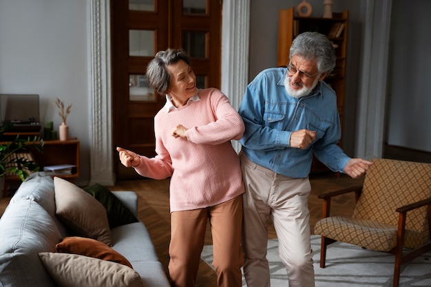 Old couple dancing at home medium shot