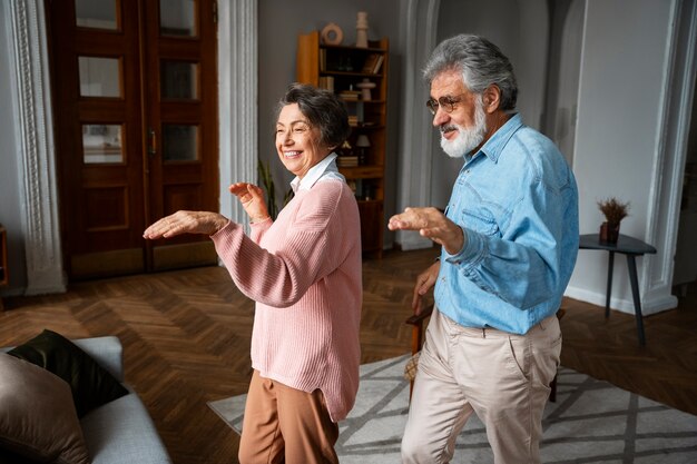Old couple dancing at home side view