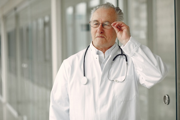 Old doctor in a uniform standing at the hall