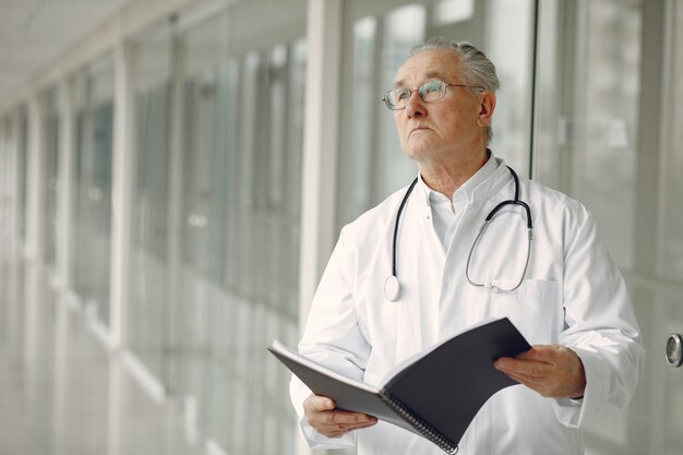 Old doctor in a uniform standing at the hall