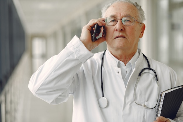 Old doctor in a uniform standing at the hall