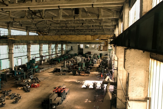 機器と機械と労働者の古い工場のホール