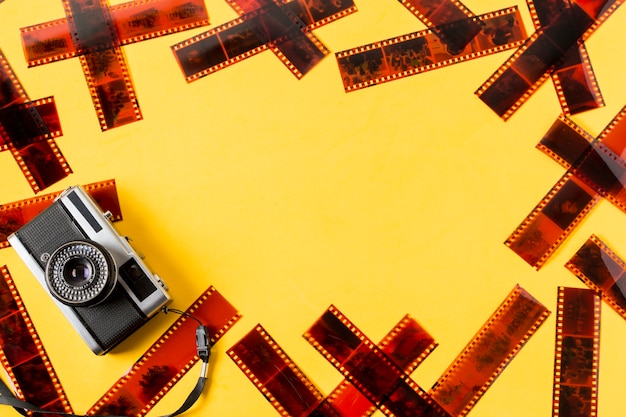 An old fashioned camera with negatives on yellow background